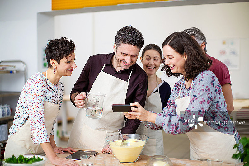 女人在烹饪课上向朋友们展示照片图片素材
