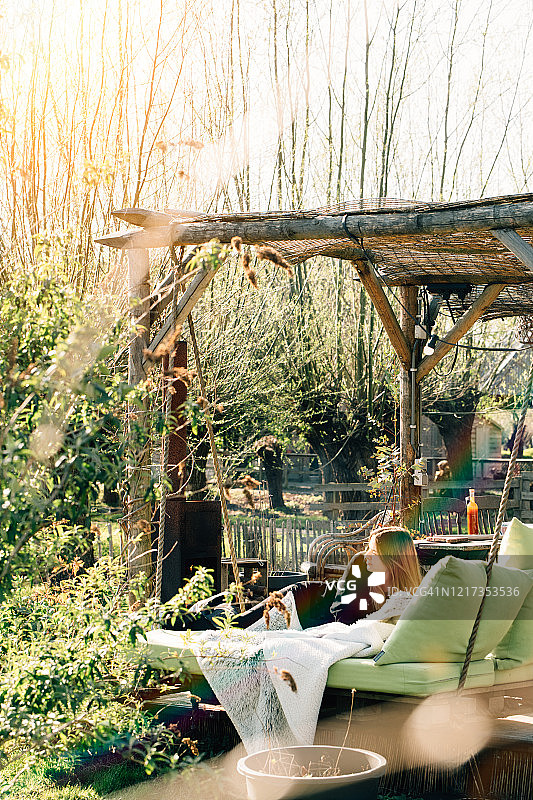 在夏日花园的躺椅上的青少年与春季鲜花图片素材