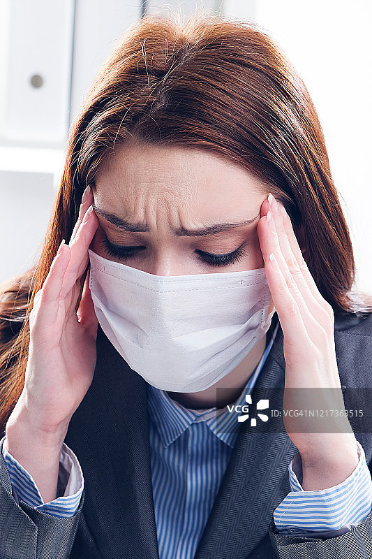 戴着防护口罩的生病女商人正在办公室工作图片素材