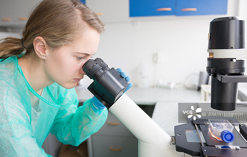 年轻女子在显微镜下研究病毒行为图片素材