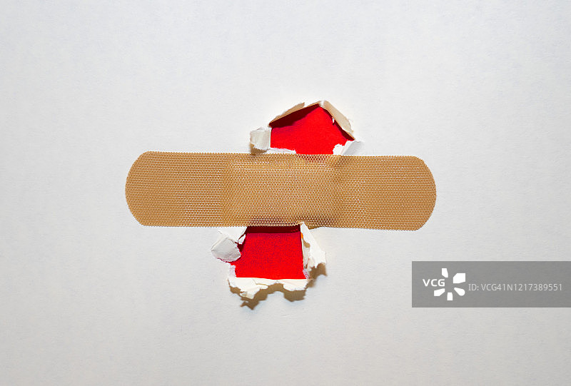 用创可贴盖住纸上的破洞。图片素材