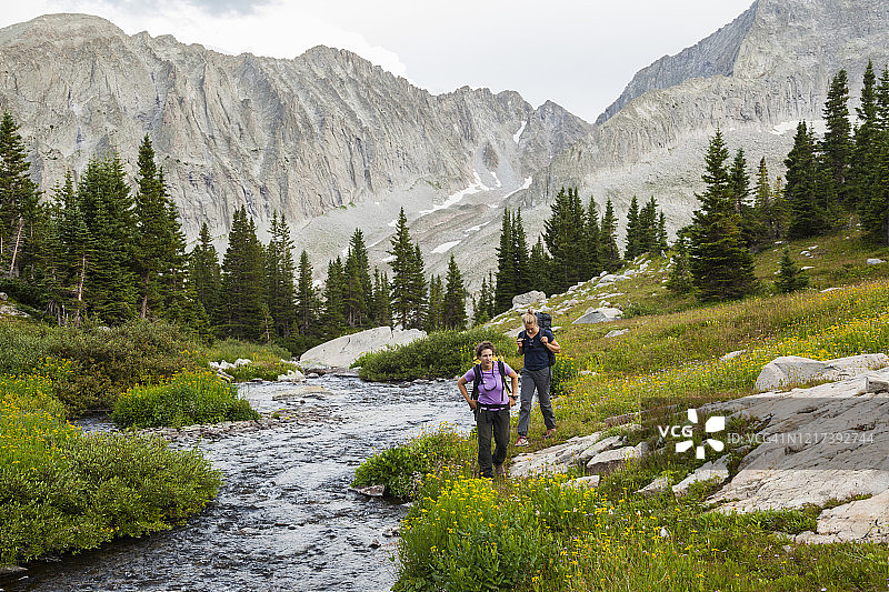 女性在科罗拉多州埃尔克山脉沿着小溪和草地徒步前往皮埃尔湖图片素材