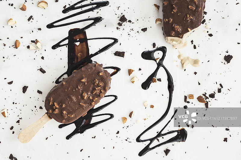 淋有巧克力酱和坚果的白色背景巧克力冰淇淋棒图片素材