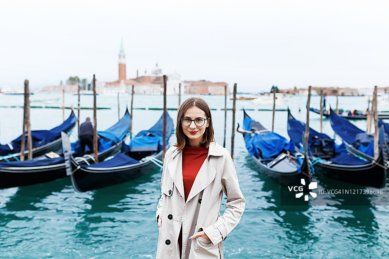 穿着连衣裙和外套的女孩，背景是运河和贡多拉图片素材