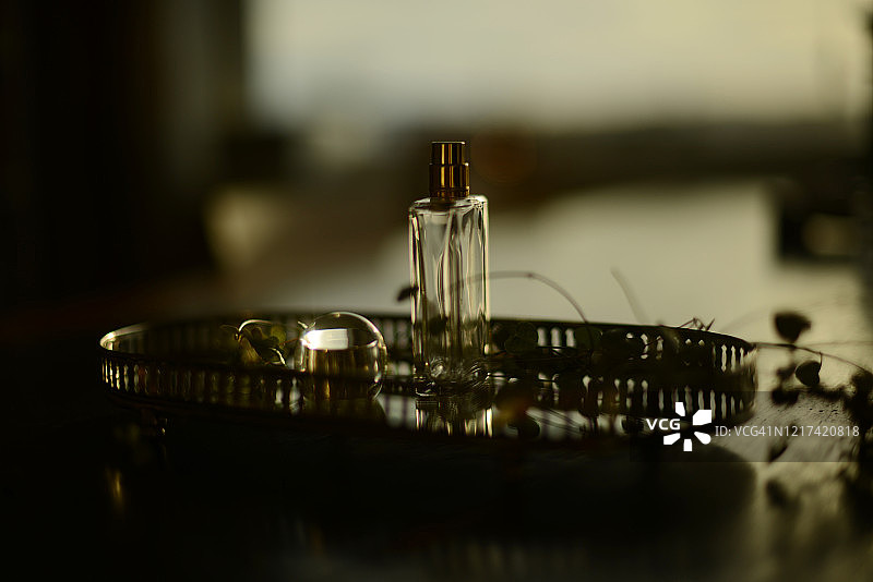 绿色植物旁银色托盘上的空香水瓶图片素材