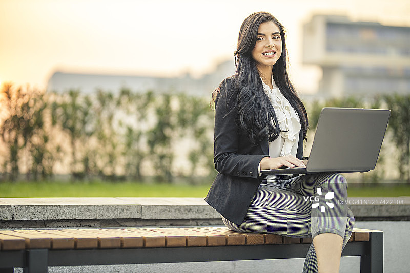 女商人在公园长椅上使用笔记本电脑图片素材