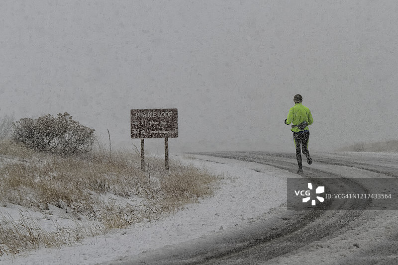 跑步者在暴风雪中在道路上奔跑图片素材