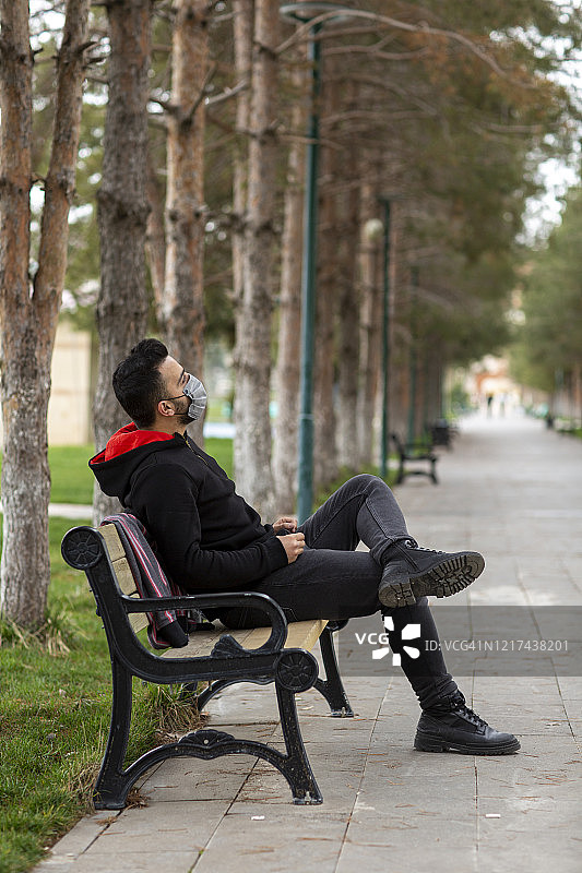 在城市公园背景下戴着医用口罩的生病男子的肖像图片素材