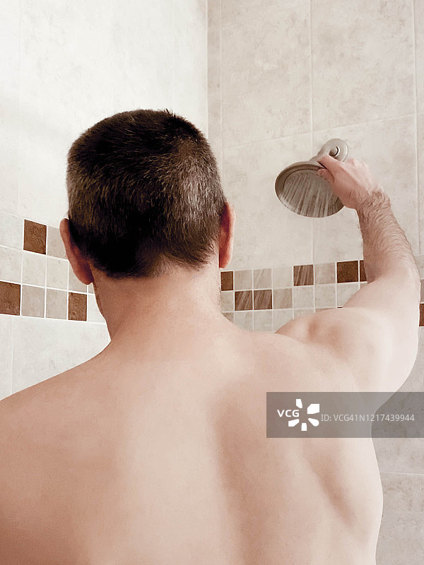 淋浴中的男人调整淋浴喷头图片素材