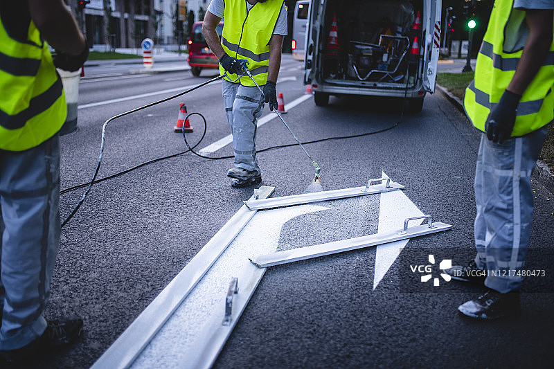 建筑队在城市街道上绘制箭头标记图片素材