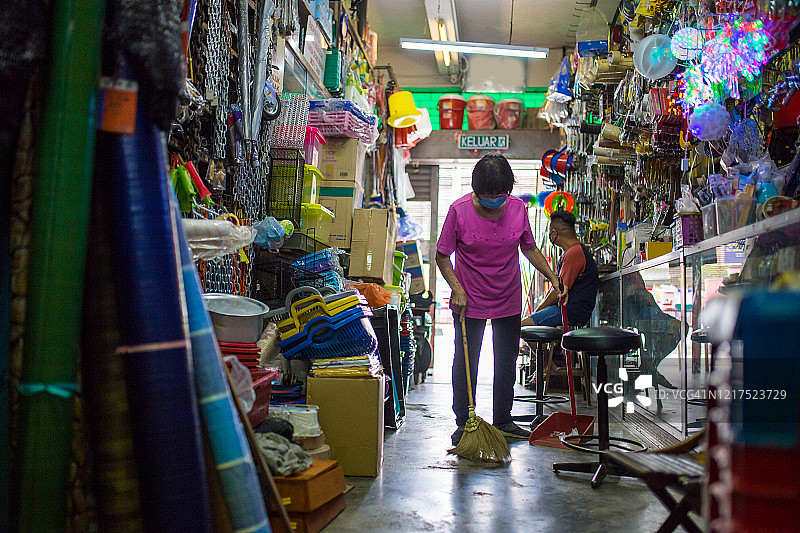 疫情封锁期间戴口罩清扫地面的亚洲女商人图片素材