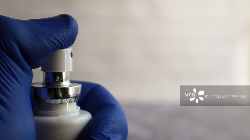 戴手套的手在白色背景上按压气溶胶防护消毒剂，预防病毒、细菌、流感和冠状病毒的健康卫生防护，留白图片素材