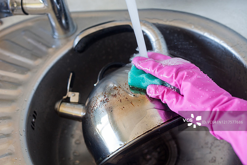 用海绵清洁脏污钢制水壶的手图片素材