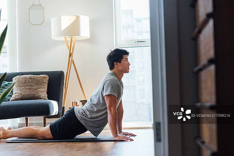 年轻男人在家做伸展运动图片素材