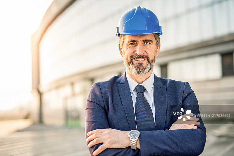 戴着安全帽看着镜头的快乐的成熟工程师肖像图片素材