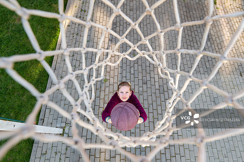 透过篮网看手拿篮球的女孩图片素材