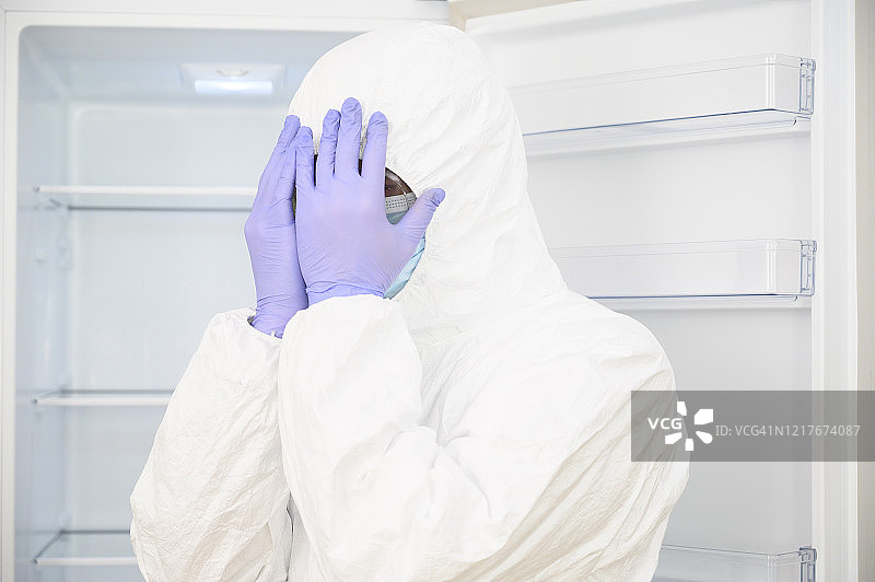 医疗失误：科学家用手捂住脸，情绪低落。他戴着口罩、手套和防护服（危险品防护服）。图片素材