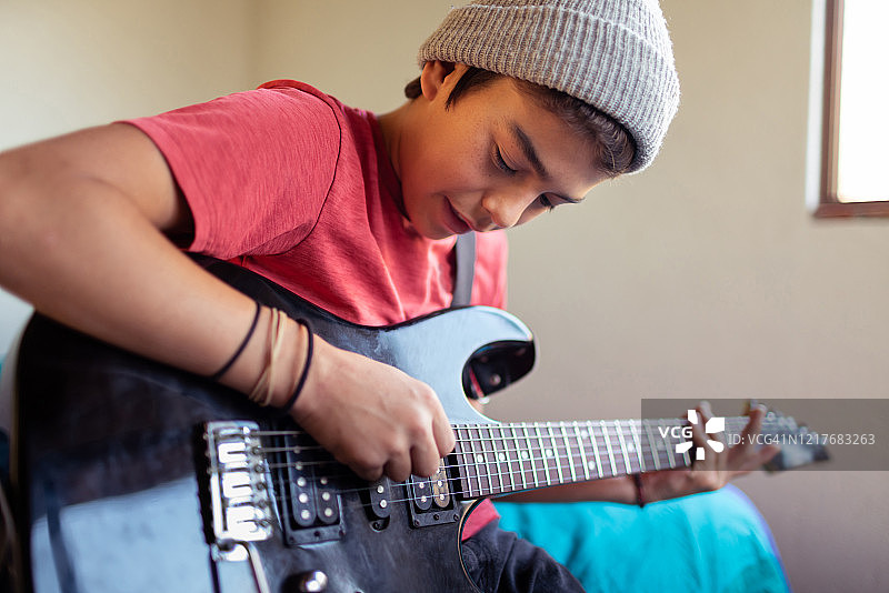 在房间里练习弹电吉他的拉丁裔儿童图片素材