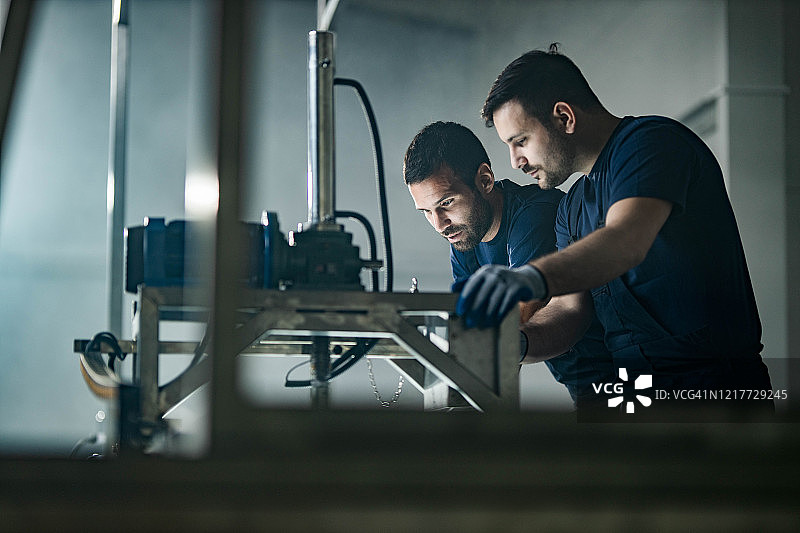 体力劳动者在工厂操作机器时合作图片素材