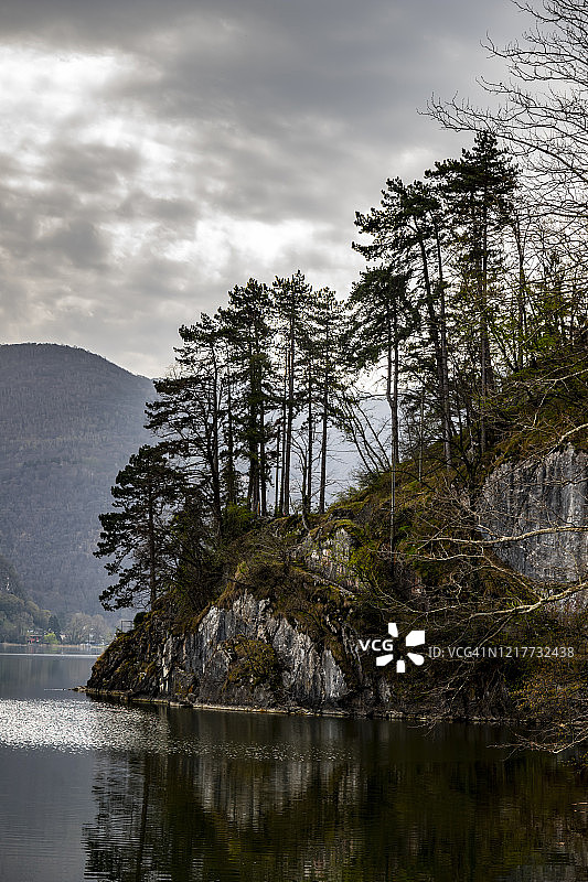 多云天气中卢加诺湖畔山上的树木图片素材