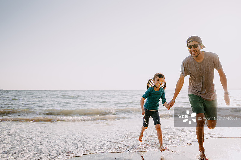父亲和小女孩躲避海浪奔跑图片素材