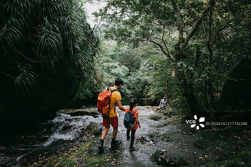 父子在冲绳丛林中的河流中徒步旅行图片素材