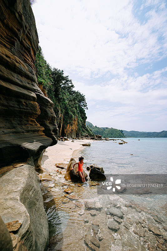 冲绳，日本，悬崖边的幽静热带海滩上的小女孩图片素材