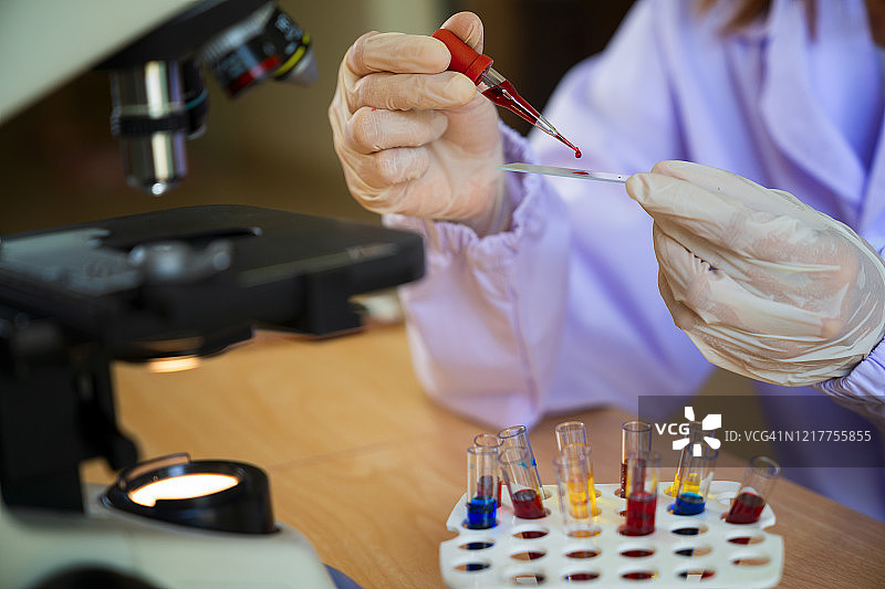 科学家用移液器将血液样本滴在研究实验室的载玻片显微镜上的镜头图片素材