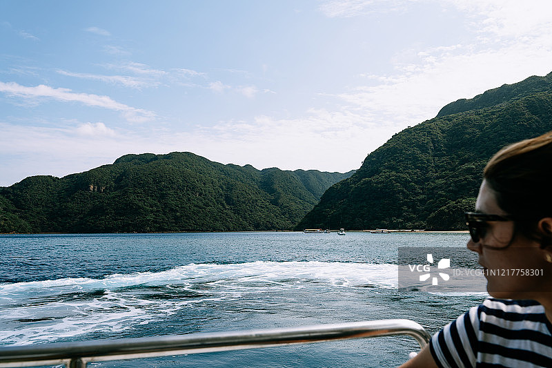 在船上看着茂盛绿色岛屿的女人图片素材