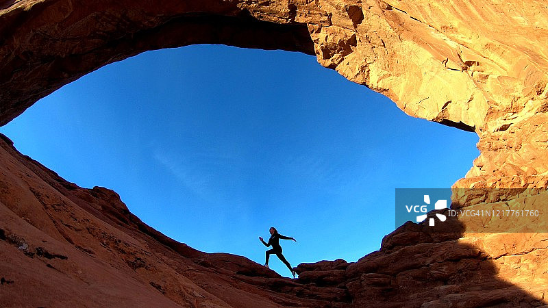 女孩在拱门国家公园的天然拱门下奔跑图片素材