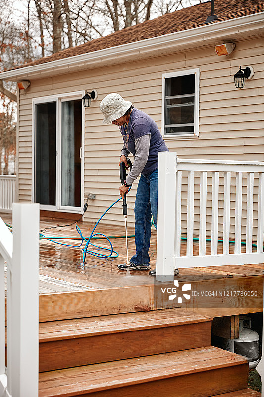 女人用高压清洗机清洁木制露台图片素材