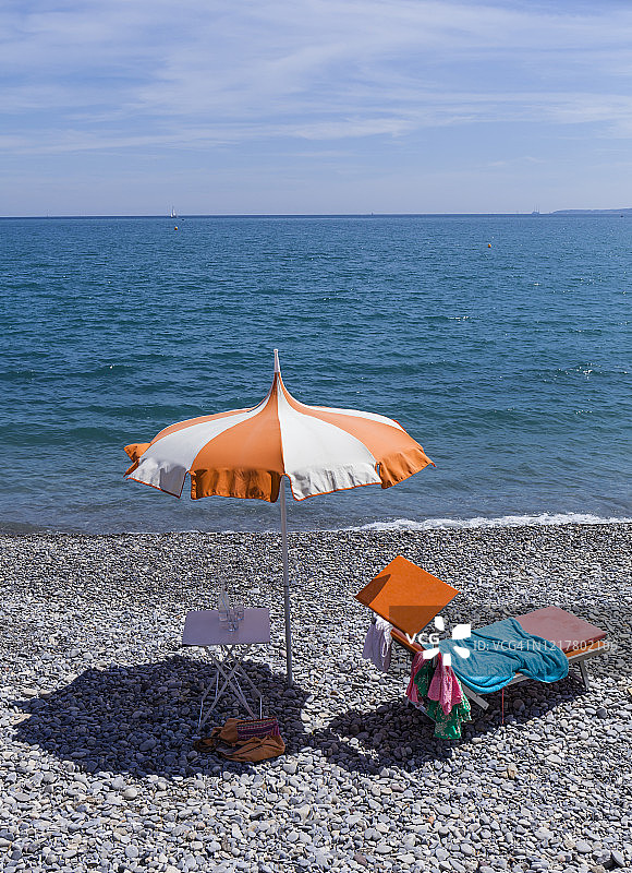 法国滨海阿尔卑斯省卡涅：地中海沿岸岩石海滩上的遮阳伞和躺椅图片素材