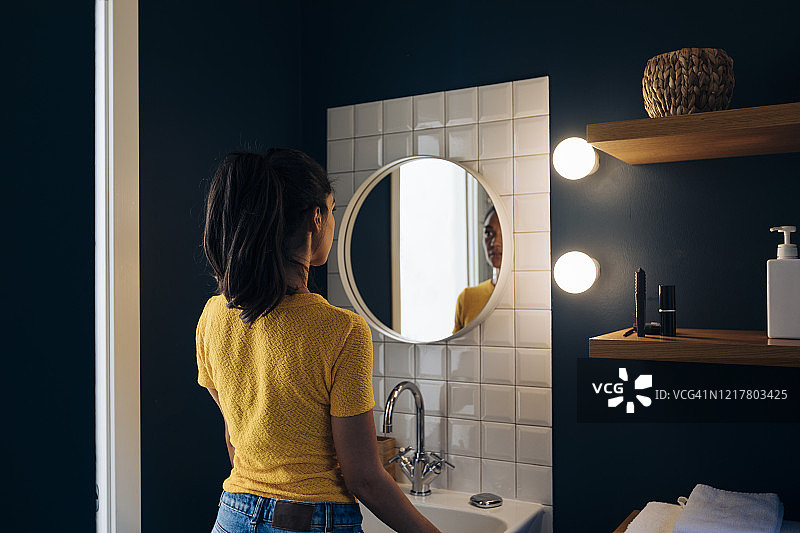 年轻女人照着浴室镜子图片素材
