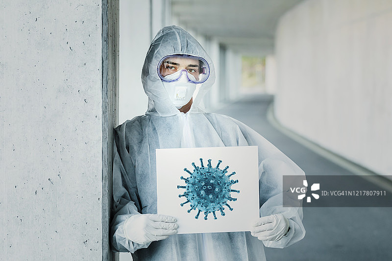 穿着防护服，拿着带有病毒图案标志的男人肖像图片素材