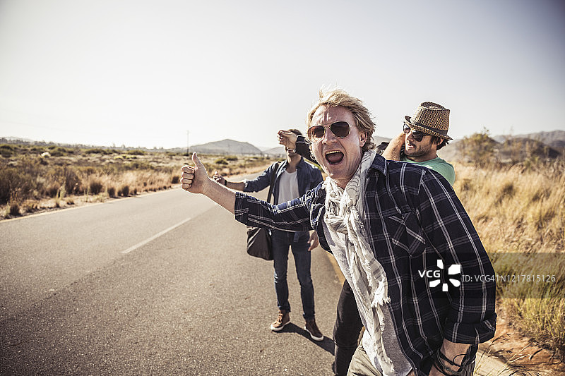 三个男人在乡村公路搭便车图片素材