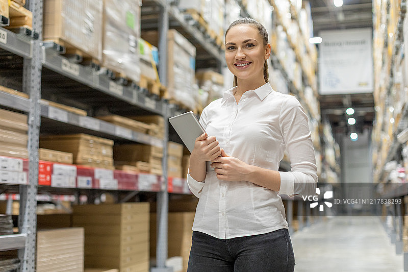 年轻女人在仓库里手持平板电脑图片素材