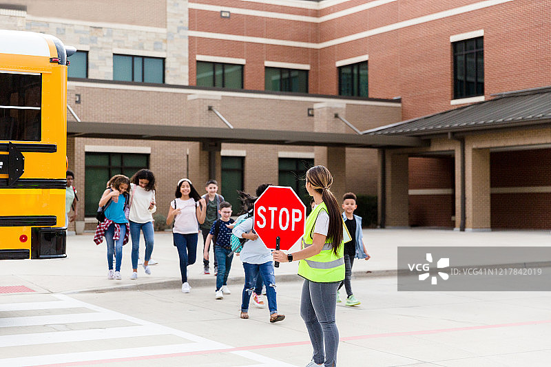 交通管理员拦停车辆，确保儿童安全过马路图片素材