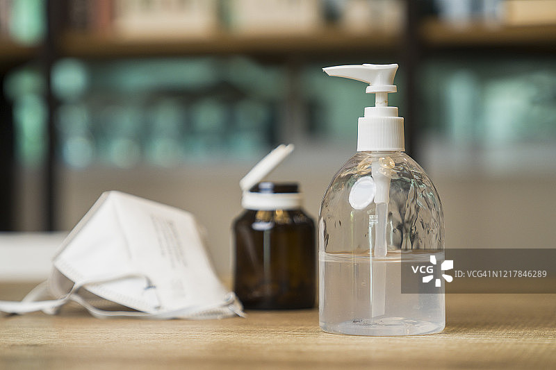 预防旅行外科卫生口罩和酒精凝胶消毒剂洗手液，人们使用酒精凝胶洗手以预防冠状病毒图片素材