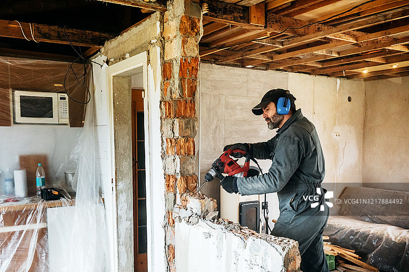 中年工人在房子里用钻头拆墙图片素材