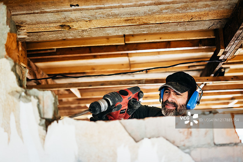 在家中损坏墙壁的工人图片素材