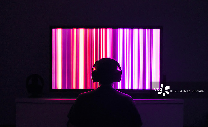 人物戴着耳机坐在电视屏幕前图片素材