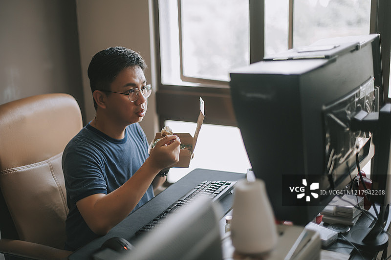 中国中年男子在家办公时享用午餐图片素材