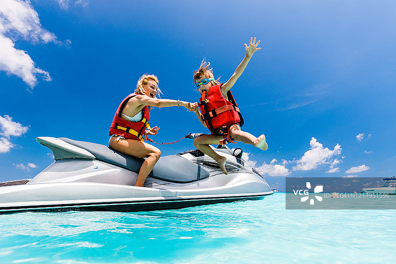 快乐的单身母亲和儿子在海上乘坐喷射快艇玩耍图片素材