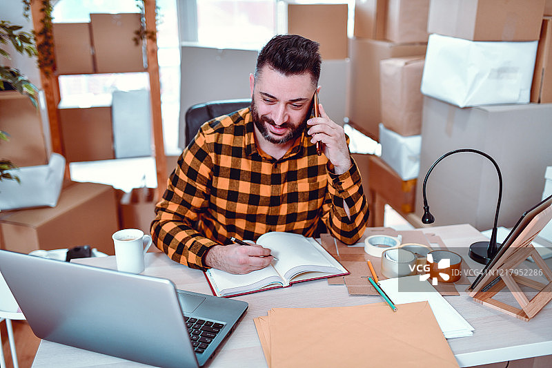 英俊男人在快递站用手机记录包裹信息图片素材