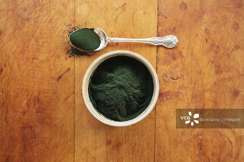 碗和勺子里的螺旋藻，木质背景图片素材
