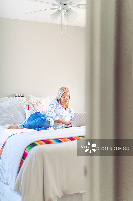 女人坐在床上使用笔记本电脑，远程医疗，网上购物，远程办公图片素材