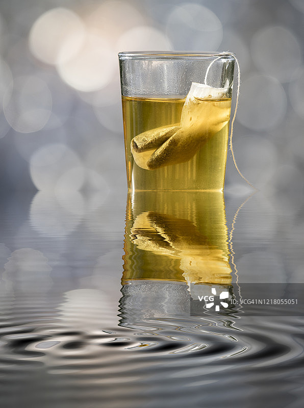 装满草药茶（茶包）的玻璃杯，阳光在水中反射图片素材