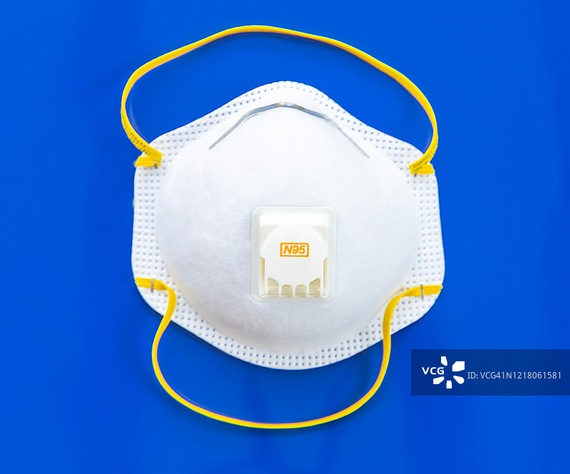 隔离在蓝色背景上的医用N95呼吸面罩图片素材