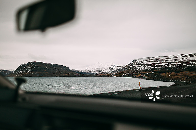 冬季冰岛公路、湖泊和雪山侧视图图片素材