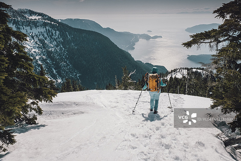 年轻女子在豪湾和太平洋上方白雪皑皑的山脊上徒步图片素材